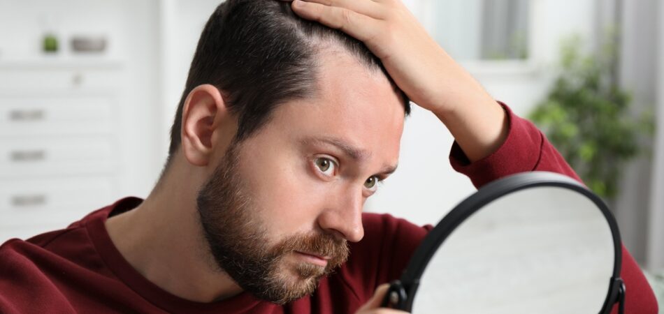 Man,with,hair,loss,problem,looking,at,mirror,indoors
