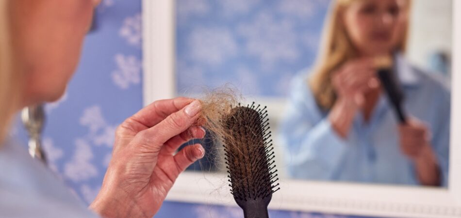 Menopausal,mature,woman,suffering,hair,loss,brushing,hair,in,mirror